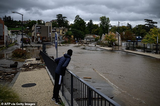 A pedestrian looks on, near a flooded street following heavy rainfall in Annonay, central France today