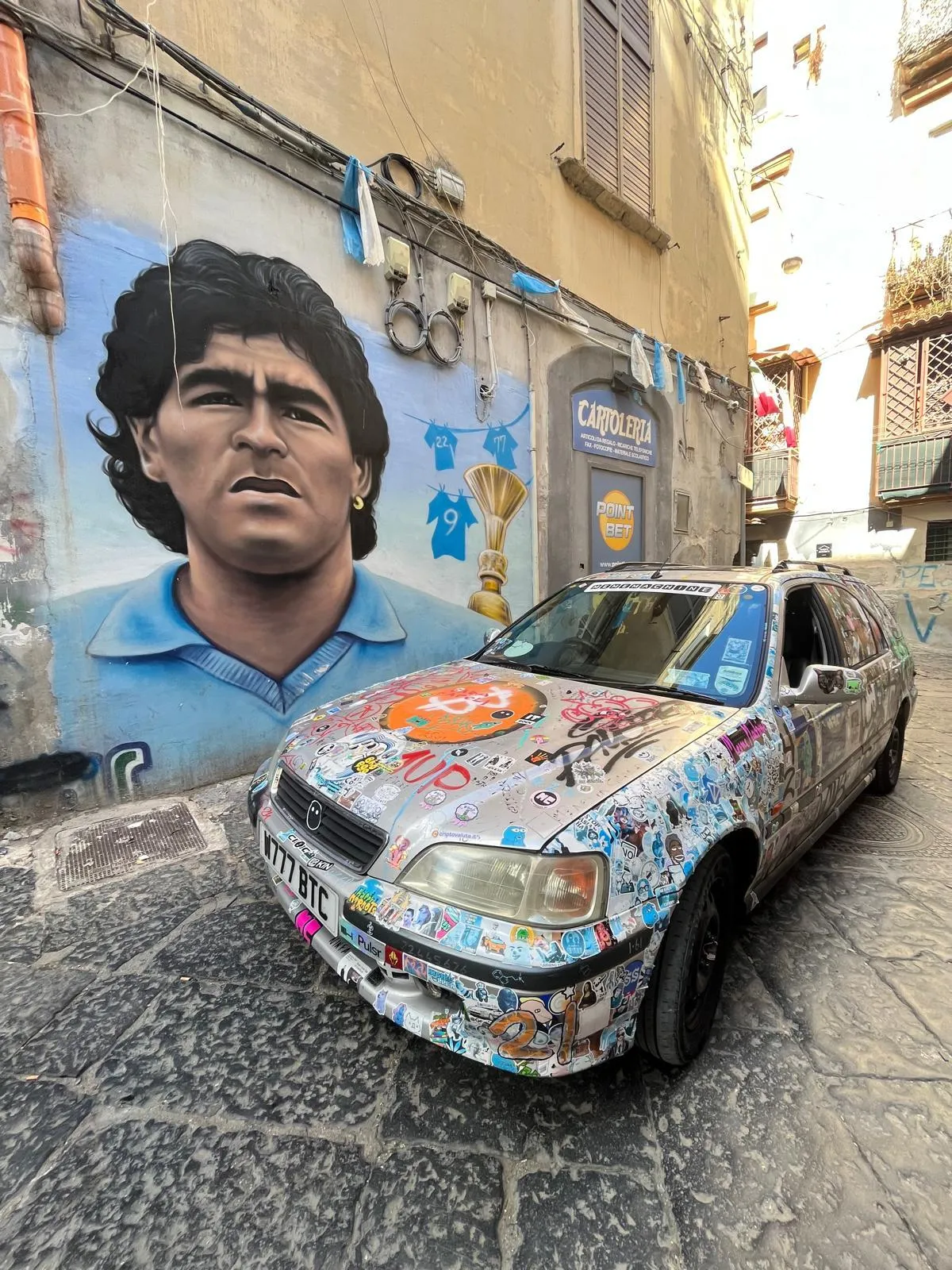 The Meme Machine in Naples in front of a graffitied picture of Maradona.