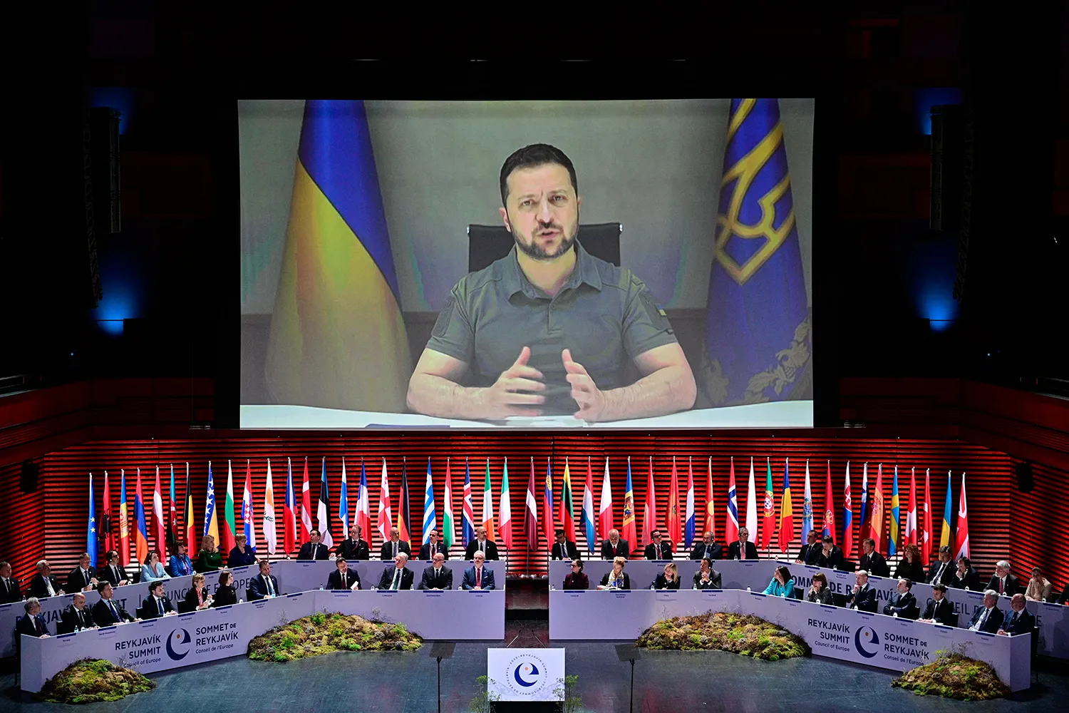 A projection of Ukrainian President Volodymyr Zelensky speaking to participants gathered on stage with the flags member states behind them at the Summit of the Heads of State and Government of the Council of Europe on May 16, 2023 in Reykjavik, Iceland.