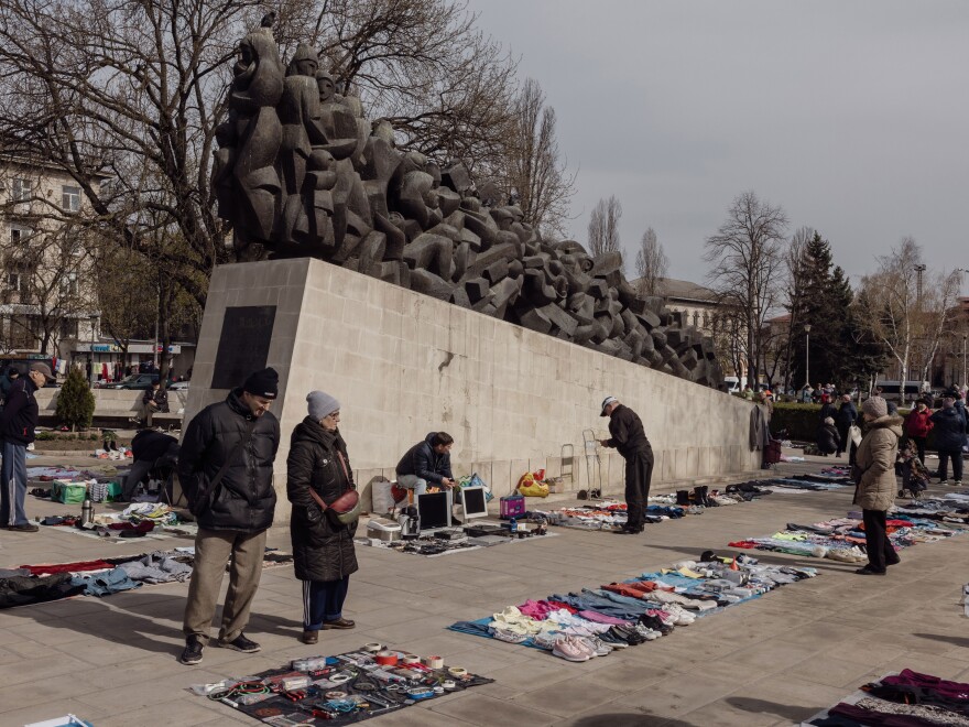 An open-air flea market where unlicensed vendors sell their wares near the railway station in Chisinau, Moldova, April 1, 2023. In the background, is a monument to the thousands of Moldovans who were deported in the 1940s and 1950s by the Stalinist-communist regime.