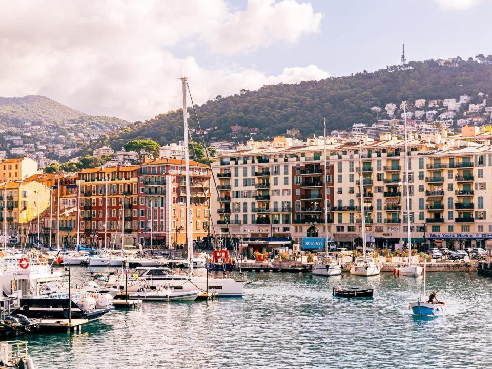 Boats in the water at a port in Nice, France. There are lots of colorful buildings on the coast.