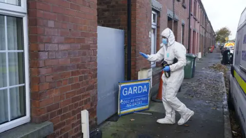 Niall Carson/PA Wire A masked Gardai forensic officer in Dundalk pictured during a search of a house linked to the investigation into the suspected murder of eight-year-old Kyran Durnin