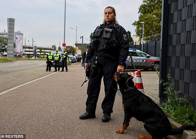 A German police officer stands guard next to a dog at a border with France, as all German land borders are subject to random controls to protect internal security and reduce irregular migration, in Kehl, Germany