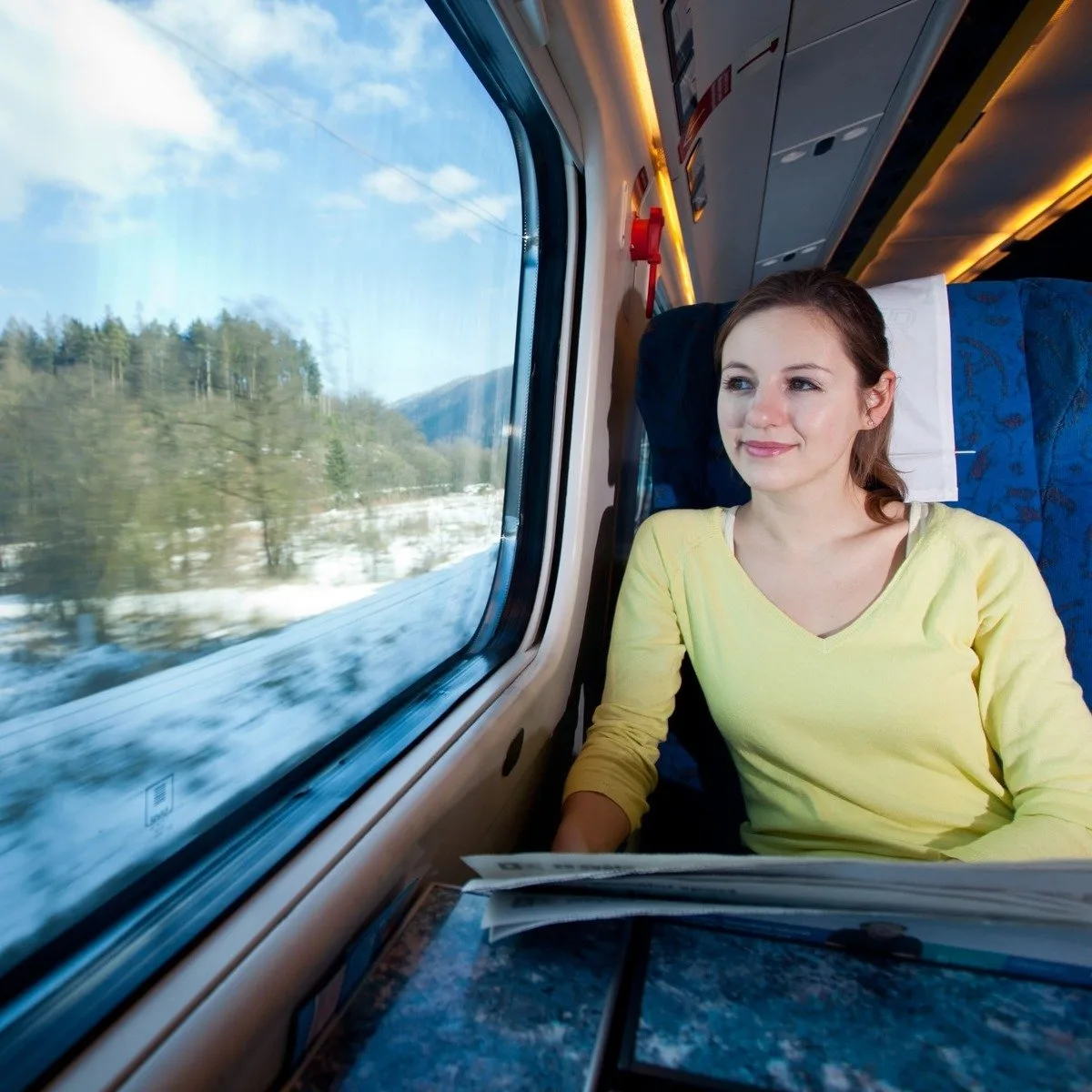 Young Woman Admiring A View Of A Snowy Landscape As She Travels In A Train In Europe