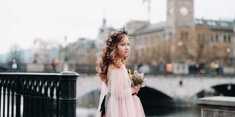 best time to visit switzerland A little girl in a pink Princess dress with a bouquet in her hands walks through the old city of Zurich.