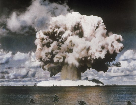 A mushroom cloud in the distance during a nuclear bomb test.