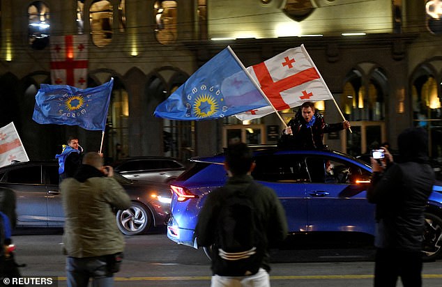 Supporters of the Georgian Dream party wave Georgian flags and the party's flags from cars after the announcement of exit poll results in parliamentary elections, in Tbilisi, Georgia October 26, 2024