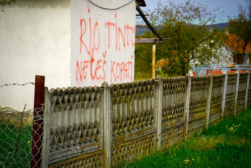 The side of a rural building, with graffiti on the side of it.