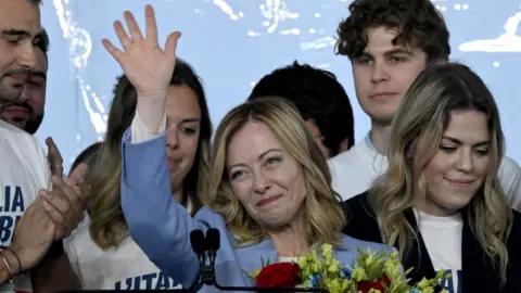 TIZIANA FABI/AFP Italy's Prime Minister, Giorgia Meloni stands on stage surrounded by young people after her speech during the campaign meeting of the far-right party Fratelli d'Italia (Brothers of Italy) ahead of the European Elections, on April 28, 2024