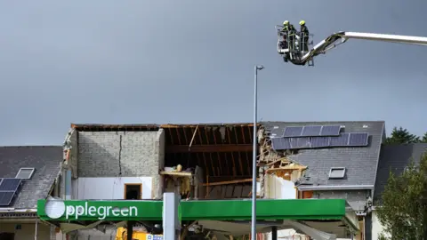 PA The building where the explosion took place, three quarters of the roof has been destroyed. At the front of the building, which would have been the roof over the fuel pumps, remains of the green 'Applegreen' sign are present.