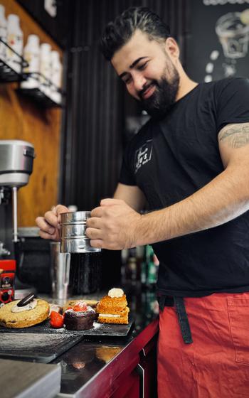 The owner of Leo’s Coffee Car shakes powdered sugar on a confection.