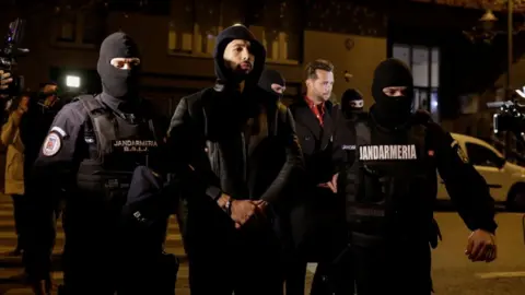 Reuters Andrew Tate and Tristan Tate are escorted by police officers outside the headquarters of the Directorate for Investigating Organized Crime and Terrorism in Bucharest (DIICOT)