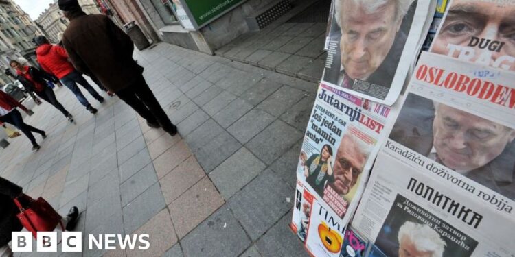 People pass by a kiosk in the main street of Bosnia and Herzegovina's capital Sarajevo, with all newspapers' frontpages displaying former Bosnian Serb leader Radovan Karadzic on March 21, 2019