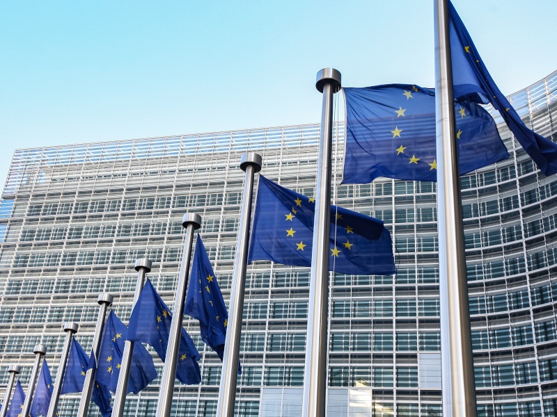 A low angle shot of the European Commission building with the EU flags in the front.