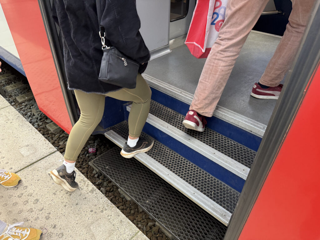 Passengers are walking up stairs into the rail car.