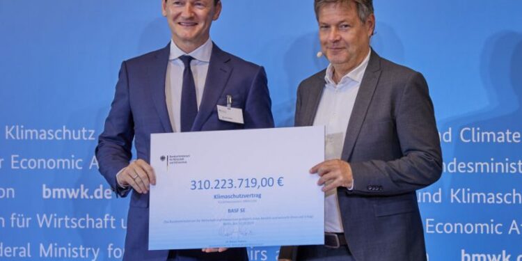BASF plant manager Uwe Liebelt holding his symbolic cheque as a Carbon Contract winner alongside German Economy and Climate Minister Robert Habeck. [Joerg Carstensen/dpa]