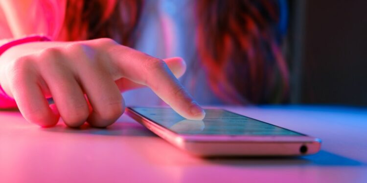 person touching a smartphone laying on a table.