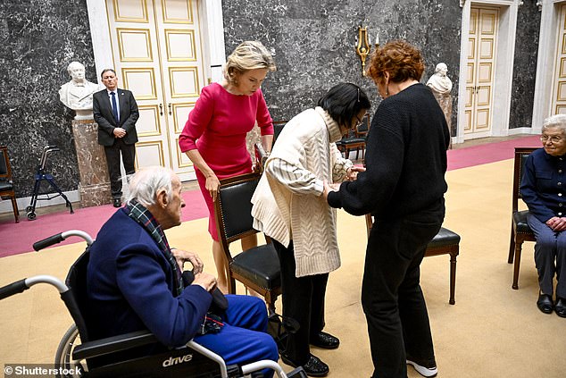 Queen Mathilde proved she's an expert in etiquette after she helped a woman into her chair this afternoon at a mental health symposium for the elderly