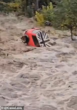 Mini Cooper is seen being dragged by flood water