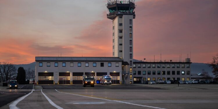 A pink sky hints at the rising sun behind a building with a control tower.