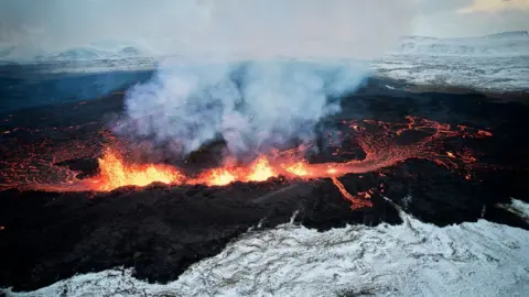 EPA An aerial view taken with a drone shows lava and smoke spewing from a volcanic fissure during an eruption, near the town of Grindavik, in the Reykjanes peninsula, southwestern Iceland, 19 December 2023.