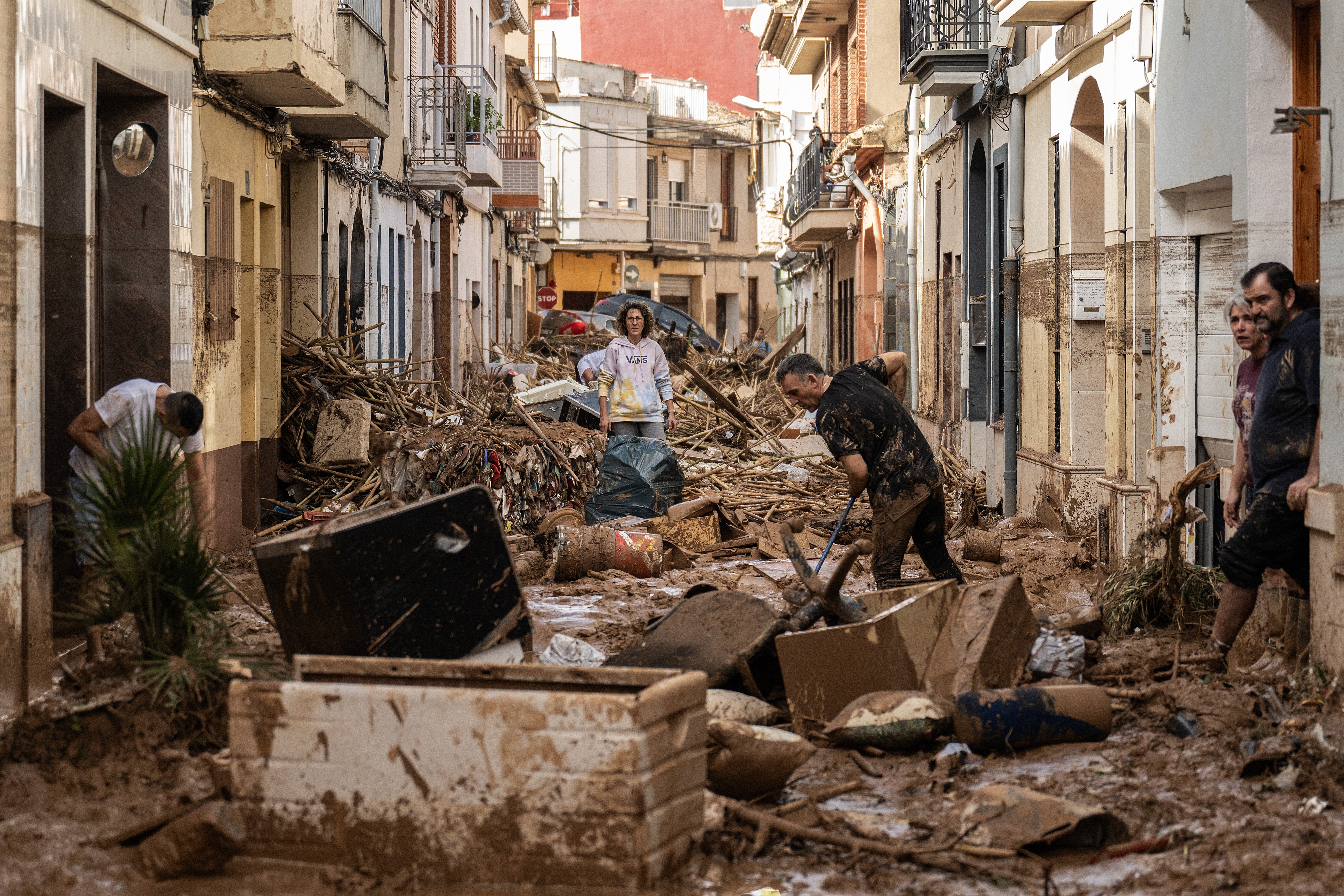 Residents clean up a mud-and-debris-covered street after flooding hit large parts of the country