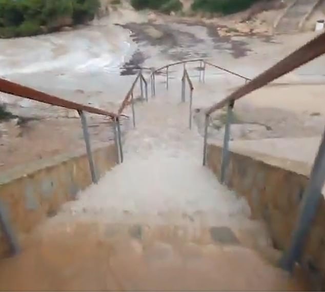 Water streams down a stairs in a town in Majorca as the roads are submerged by high floodwaters