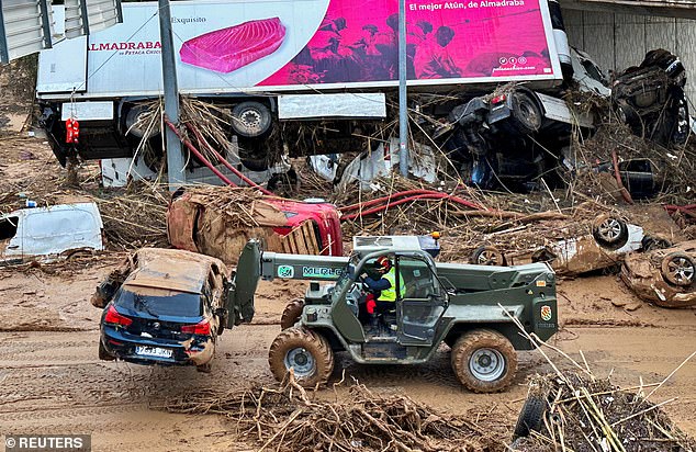 A vehicle from Spain's Military Emergency Unit (UME) cleans up destroyed cars on a highway, in the aftermath of floods, in Torrent, near Valencia, Spain, November 1, 2024