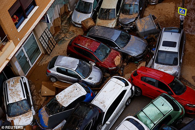 A man looks from his window at piled cars after heavy rains in Sedavi, in Valencia, Spain, October 31, 2024