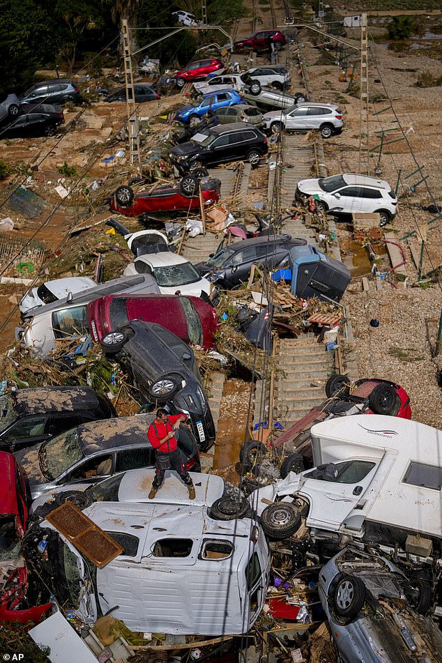 A man stands among flooded cars piled up in Valencia, Spain, Thursday, Oct. 31, 2024