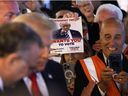 An onlooker holds up a voting flyer as Republican presidential nominee former President Donald Trump visits The Great Commoner cafe on November 01, 2024 in Dearborn, Michigan.  