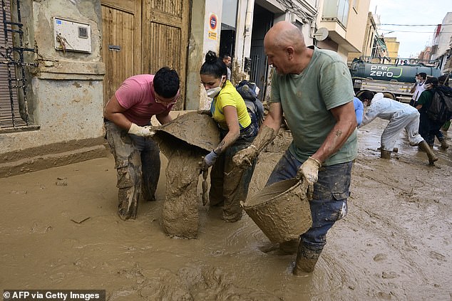 People pour in the street the mud removed from the houses in Massanassa, region of Valencia, eastern Spain