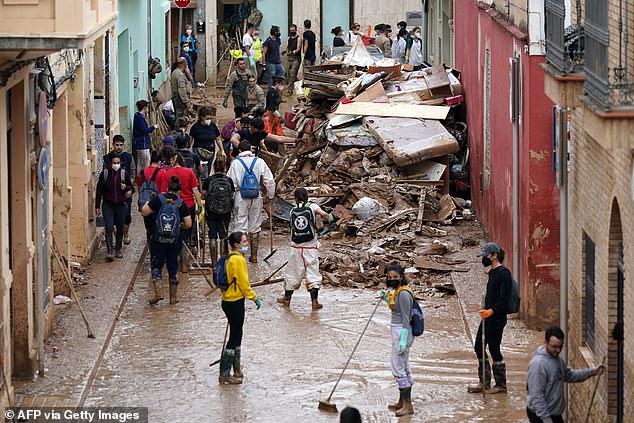 People try to drag mud on a street full of debris in Catarroja, region of Valencia, eastern Spain