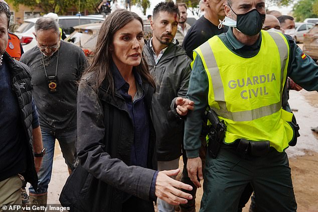 Queen Letizia of Spain, with mud stains on her face, approaches to speak with a town resident during the Spanish royal couple's visit to Paiporta on November 3