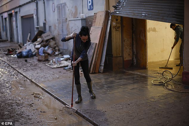 Neighbours clean a damaged house and sidewalk in Paiporta, Valencia after horrific flooding