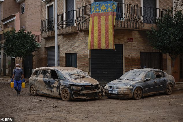 The region faced a similar, but less ferocious, flood in 1957, during which 81 people died (A man walks past two cars damaged in a street of Paiporta)