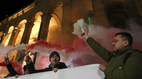 Reuters Demonstrators hold flares in Georgia's capital Tbilisi