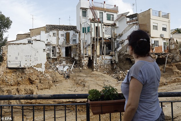 A woman looks at a mud-covered road and damaged houses in the flood-hit municipality of Chiva, near Valencia, Spain, 31 October 2024