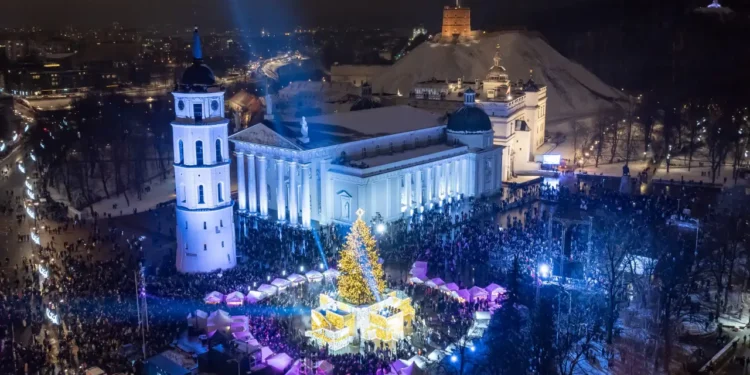 Aerial view of Vilnius’s Cathedral Square during Christmas, featuring a beautifully lit Christmas tree surrounded by festive markets and crowds.