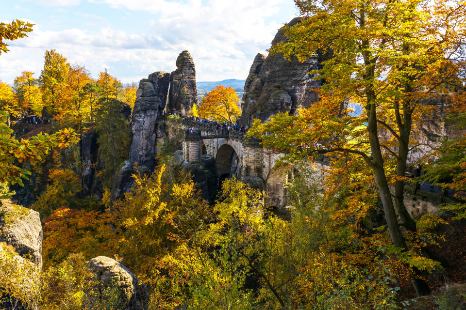 Bastei-Bridge (Basteibrücke) in the Elbe Sandstone Mountains in autumn colors.

The Bastei is a rock formation towering 194 metres above the Elbe River in the Elbe Sandstone Mountains of Germany. Reaching a height of 305 metres above sea level, the jagged rocks of the Bastei were formed by water erosion over one million years ago. The Bastei has been a tourist attraction for over 200 years. In 1824, a wooden bridge was constructed to link several rocks for the visitors. This bridge was replaced in 1851 by the present Bastei Bridge made of sandstone.