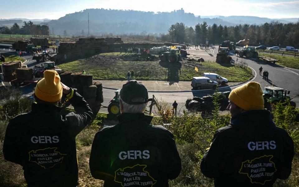 Farmers watch a blockade being built with 578 bales of straw in Auch, south-west France