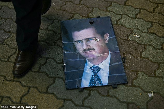 A man walks past a portrait of ousted president Bashar al-Assad on the ground as people gather at Saadallah al-Jabiri Square after the Friday noon prayer in Aleppo