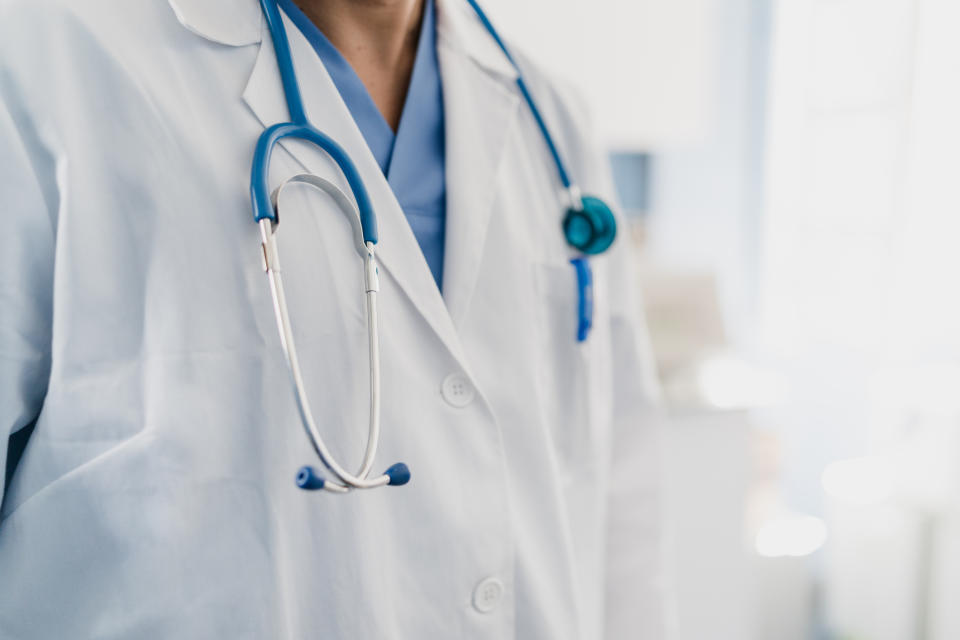 Person wearing a white lab coat and stethoscope, suggesting a healthcare professional in a medical setting