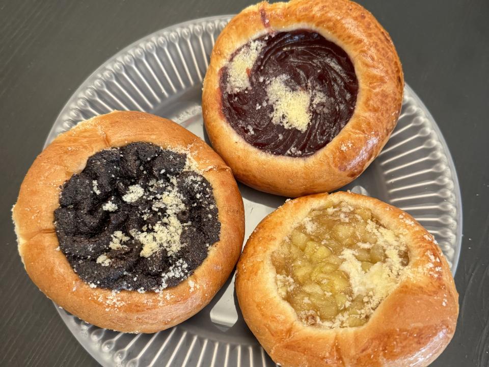 Three pastries with fruit in the middle of each on a clear plate.