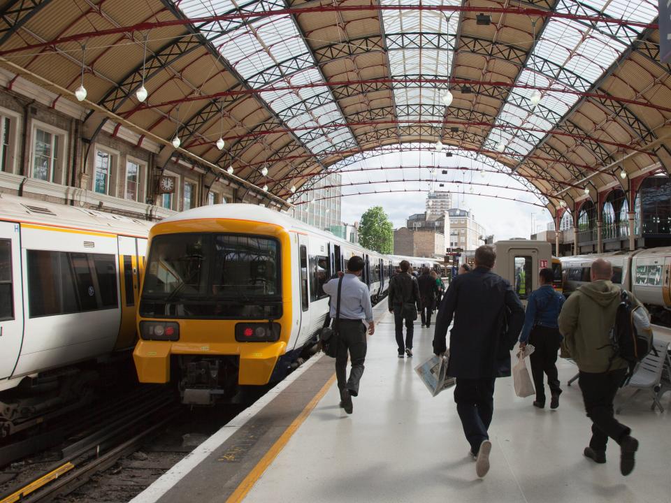 People walking toward one of a few trains in a station.