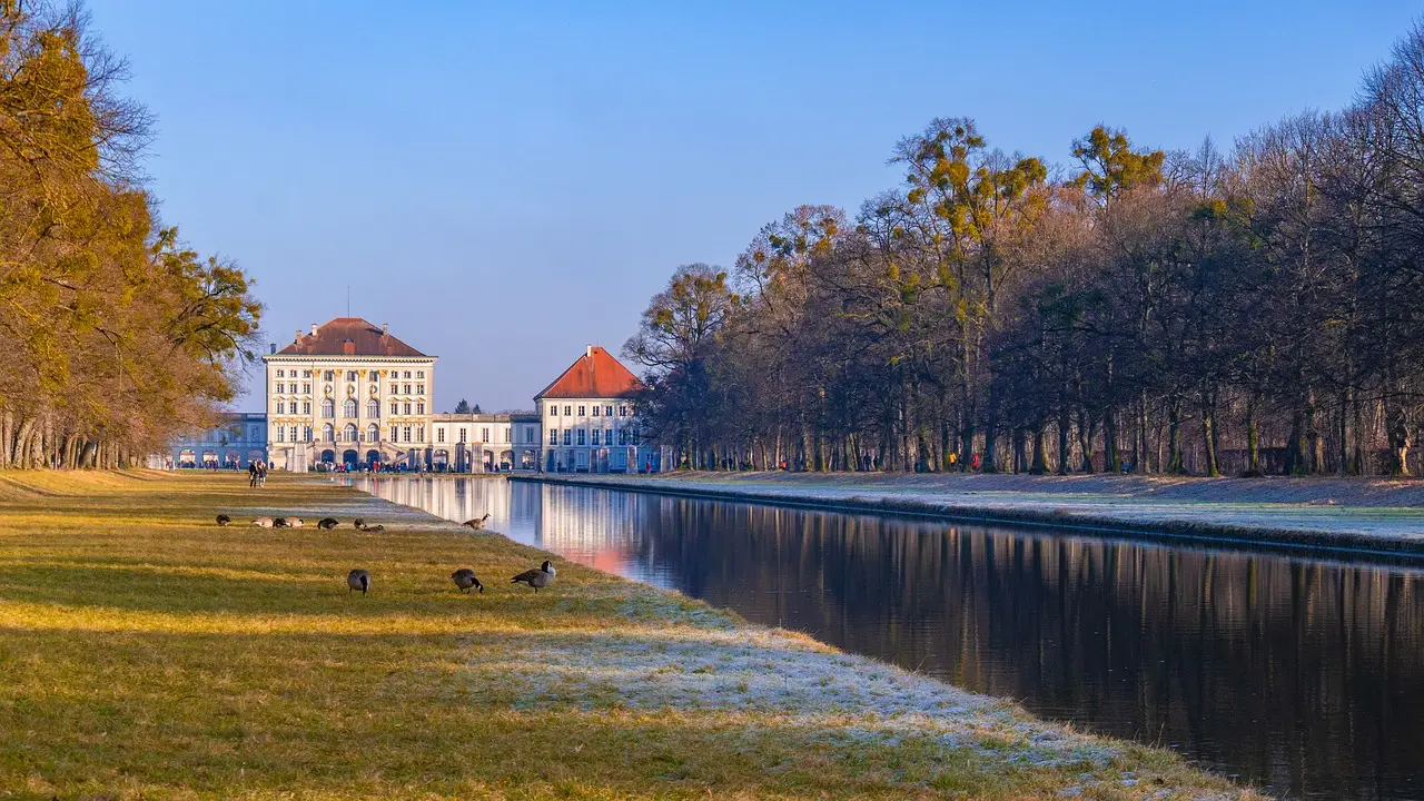 Nymphenburg Palace in Munich, Germany, is surrounded by beautiful gardens and a calm reflecting canal during autumn.