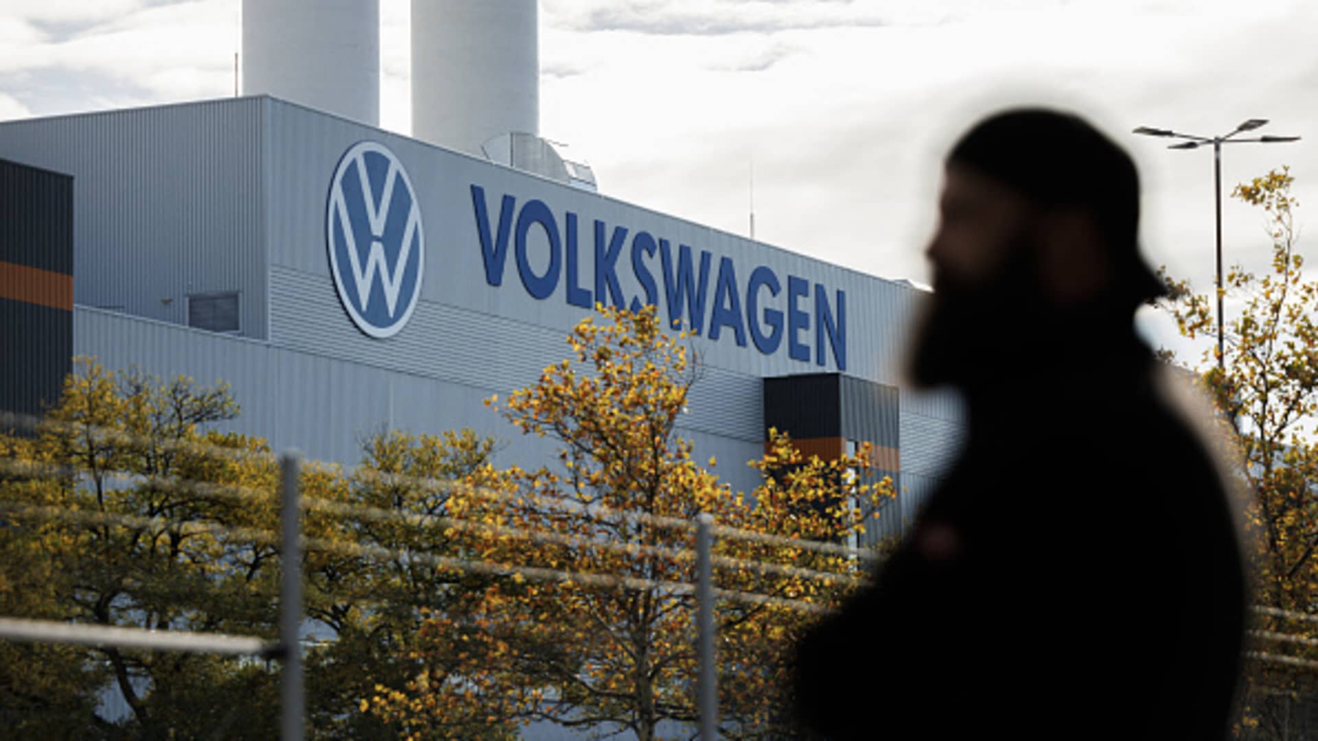 An employee of the Volkswagen plant in Zwickau stands next to the VW logo on the factory premises during an information event organised by the Works Council of Volkswagen Saxony in Zwickau, eastern Germany, on October 28, 2024. 