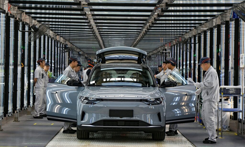 Workers complete assembling an electric vehicle (EV) at China