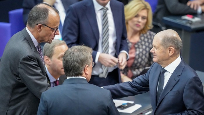 German Chancellor Olaf Scholz, right, greets Christian Democratic Union leader Friedrich Merz, left, in the plenary chamber of the Bundestag on December 4 2024