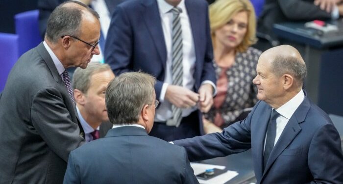 German Chancellor Olaf Scholz, right, greets Christian Democratic Union leader Friedrich Merz, left, in the plenary chamber of the Bundestag on December 4 2024